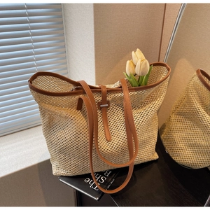 Détail du sac cabas en paille tissée avec garniture en cuir marron et boucle métallique