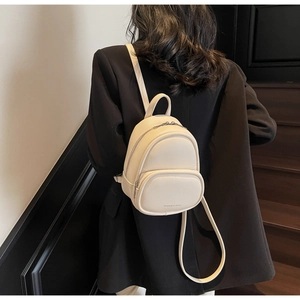 Detail view of mini off-white backpack in pebbled leather texture with silver zipper