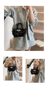 Detail of glossy black patent leather mini crossbody bag with silver lock and heart charm