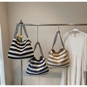 Détail du sac cabas rayé en maille avec poignée nouée décorative et texture tissée élégante