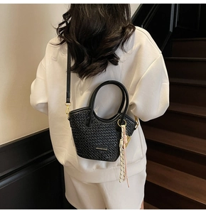 Detail view of the black woven leather texture and elegant gold metallic hardware of the handbag