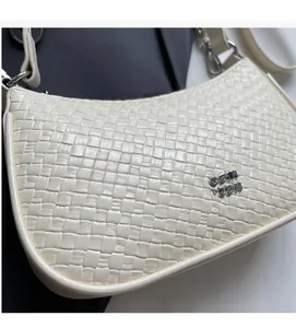 Detailed macro view of cream woven leather texture and metal CQIN ZDN logo on underarm bag