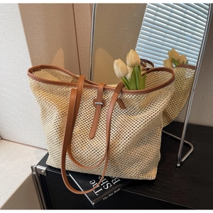 Détail d'un sac cabas en paille tissée avec anses en cuir marron et maille tressée