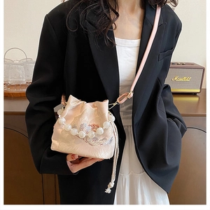 Detail of pink embroidered silk bucket bag with large pearl handle and floral pattern
