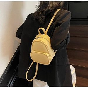 Detailed view of yellow mini backpack with litchi texture PU leather on model