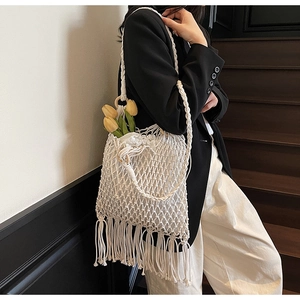 Sac évidé blanc tissé main avec détails de glands et doublure à cordon porté par modèle
