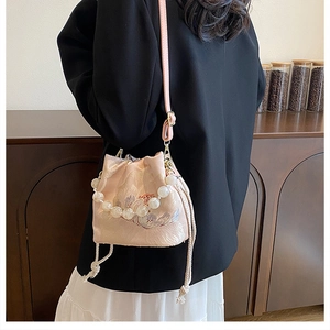 Detailed embroidery on a pink bucket bag with elegant pearl handle and satin finish