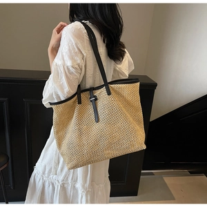 Détail du grand sac cabas en paille avec bandoulières en cuir noir et boucle décorative