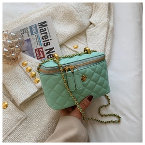 Detail of mint green quilted mini crossbody bag with golden flower accent and chain strap