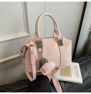 Detail of pink Boston bag showing glossy leather texture, silver buckles and heart pendant