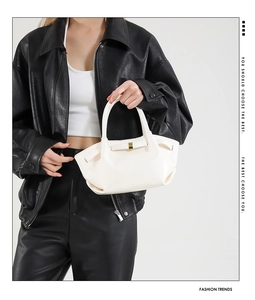 Detail of white PU leather hobo bag with pleated texture and gold buckle on a model