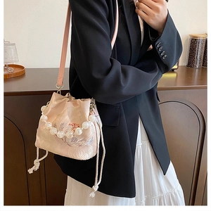 Detail of pink embroidered bucket bag with pearl handle and drawstring closure