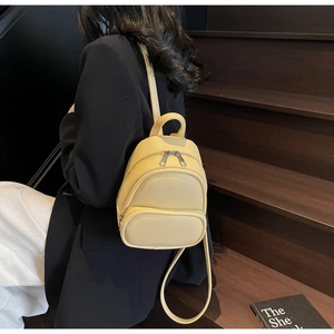 Detailed view of a mini yellow backpack with lychee grain texture on a wooden staircase