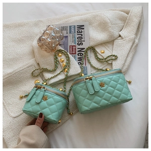 Detail of mint green quilted bucket bags with gold flower logos and chain straps