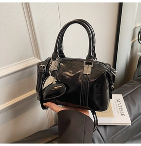 Detail of black glossy Boston bag with silver hardware and a heart-shaped charm accessory