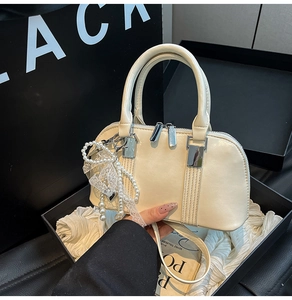 Detail der cremefarbenen Mini-Tasche mit Perlenanhänger und Silberbeschlägen im Geschenkkarton