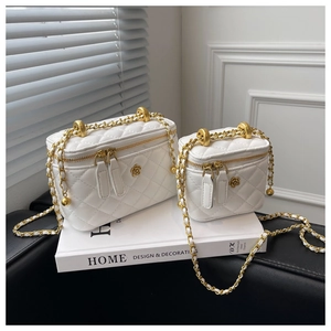 Detail of white quilted leather vanity bags with gold flower logo and metal chain straps