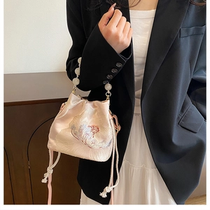 Detail of pink satin bucket bag featuring floral embroidery and luxury pearl handle