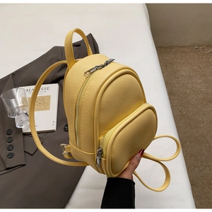 Detail of yellow pebbled leather mini backpack with dual zip compartments and sleek straps
