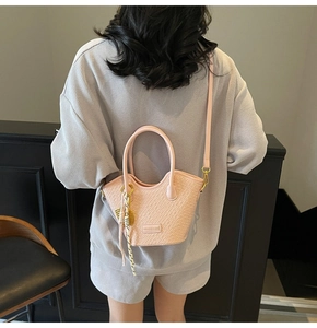 Rear view of pink crocodile pattern bucket bag with silk scarf on dark background