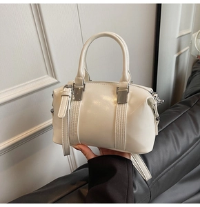 Detail of a creamy white Boston handbag featuring silver hardware and vertical seams