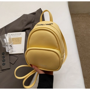 Detail of bright yellow faux leather mini backpack with silver zipper and top handle
