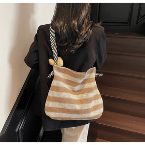 Détail du grand sac cabas en maille rayée avec une bandoulière épaisse à motifs sur l'épaule