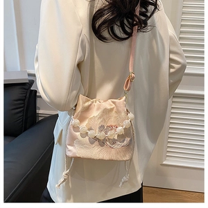 Detail of pink silk bucket bag featuring floral embroidery and elegant beaded handle