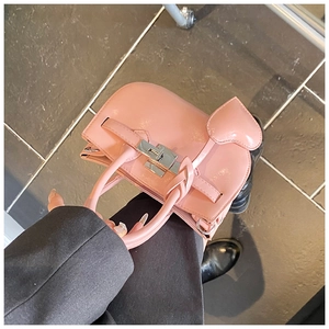 Detailed macro view of pink patent leather handbag with silver clasp and heart charm
