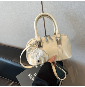 Nahaufnahme der cremefarbenen PU-Bowlingtasche mit Perlenanhänger und Silberbeschlägen
