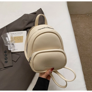 Detail of creamy white litchi grain leather mini backpack with a front zipper pocket