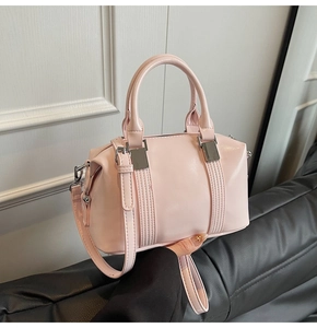 Close-up of light pink Boston bag with shiny leather texture and silver hardware