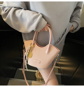 Detail of pink woven bucket bag with silk scarf handle and golden tennis racket charm