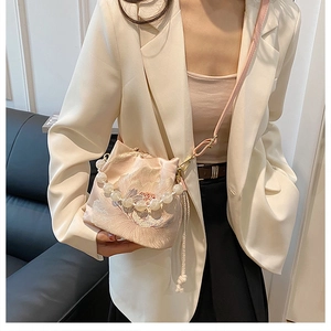 Detail of beaded bucket bag with butterfly embroidery and elegant pearl handle straps