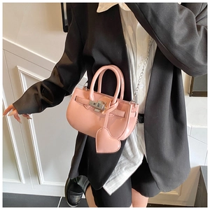 Detail of pink patent leather handbag featuring shiny metal twist lock and heart charm