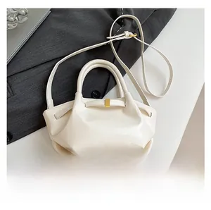 Detail of white oil wax leather bucket bag with gold buckle and circular handles