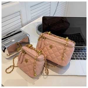 Detailed macro of pink quilted bucket bag with golden flower badge and chain strap