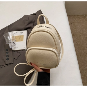 Detail of cream mini backpack in pebble leather texture with silver zipper pocket