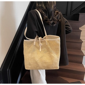 Détail d'un sac cabas en paille tissée beige avec bandoulières en cuir sur un modèle