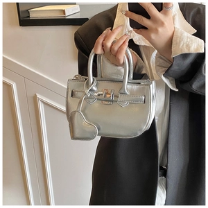 Macro detail of silver metallic mini bag with heart charm and classic flap lock design