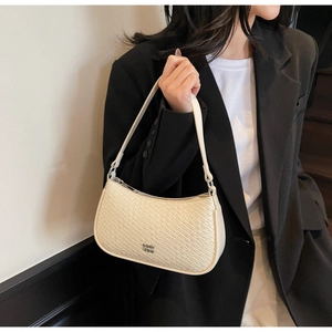 Close-up of cream faux crocodile texture shoulder bag on a black blazer outfit