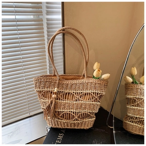 Detail of straw woven tote with hollow craft, wood bead tassels and interior lining
