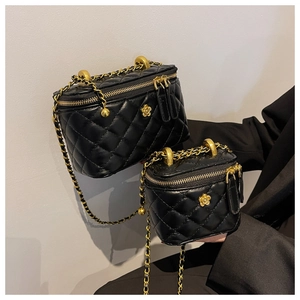 Detail of black quilted leather vanity case with golden flower buckle and chain strap