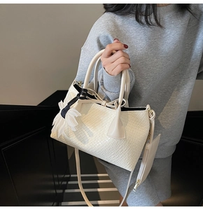 Detail of cream woven crocodile texture handbag with silk flower charm and strap
