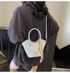 Detailed view of light blue woven texture tote bag with metallic logo and tassel charm