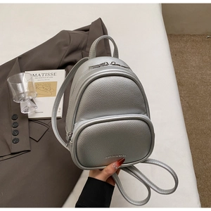 Macro shot of silver pebbled leather mini backpack with metal zipper and fashion logo