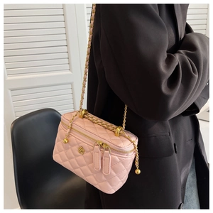 Detail of pink quilted crossbody bag with gold camellia logo and chain shoulder strap