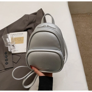 Detail shot of silver mini backpack with lychee texture and fashion logo engraving