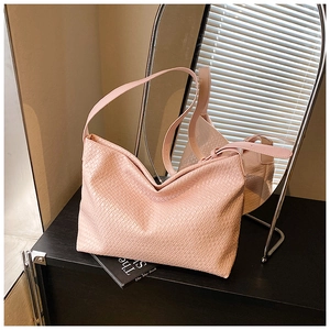 Detail of pink woven underarm tote bag featuring a textured intrecciato pattern design