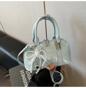 Detail einer hellblauen Handtasche aus Kunstleder mit Spitzenbogen und Perlenanhänger